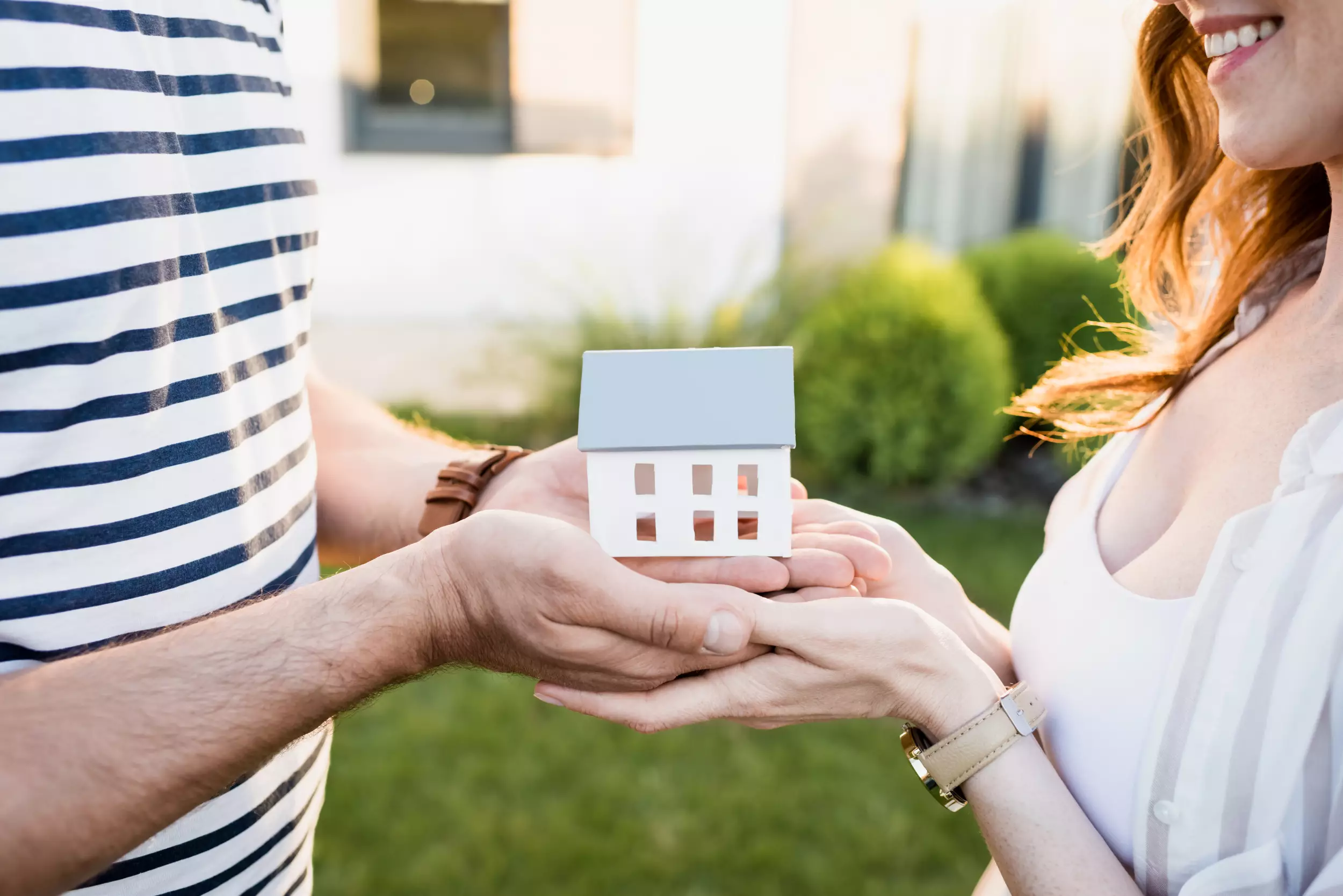 A young couple holding a model house in their hands